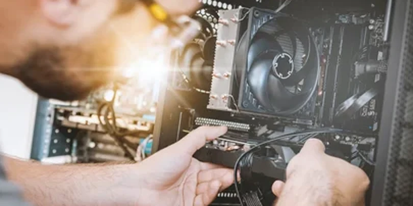 Technicien intervenant à l'intérieur d'un PC de bureau ouvert, en atelier